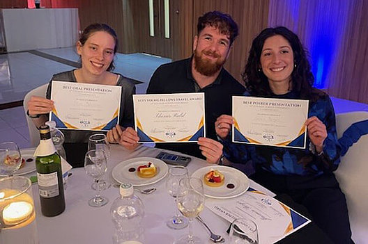Gruppenbild der deutschen Preisträger beim ECFS Basic Science Kongress auf Malta Gruppenbild an einem noch gedeckten Tisch, zwei Frauen und ein Mann halten Urkunden in die Kamera.