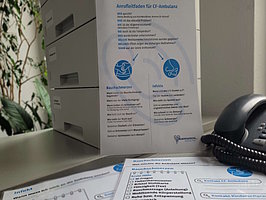 Auf dem Bild sind verschiedene laminierte Zettel und ein Telefon zu sehen