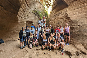 Gruppenfoto von Menschen auf Gran Canaria in einem Canyon. Man sieht Felsen im Hintergrund. Bei den Gruppenklimamaßnahmen des Mukoviszidose e.V. auf Gran Canaria werden auch gemeinsame Ausflüge gemacht. 