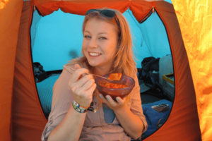 Der Klassiker beim Festival: Dosenravioli. Auf dem Bild sieht man eine Frau mit einer Schale Dosenravioli vor einem Zelt sitzen. 