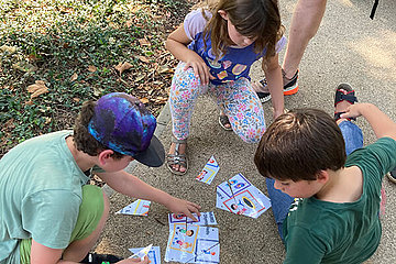 Kinder-Olympiade bei MUKOmiteinander 2024 Drei Kinder sitzen auf dem Boden im Sommer und puzzlen eine Karte zusammen. Das Foto wurde bei MUKOmiteinander 2024 aufgenommen.