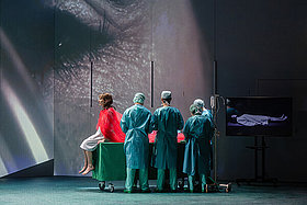 Auf einer Theaterbühne dargestellte OP-Szene mit der Hauptdarstellerin der Oper