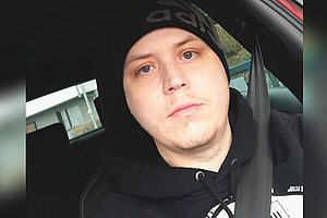 Klaus Dieter sitzt angeschnallt im Fahrersitz eines Autos. Er trägt eine schwarze Mütze. 