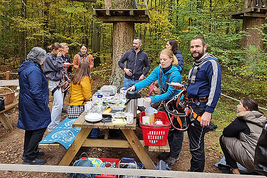 Gruppe von Menschen an einem Picknicktisch in einem Kletterpark im Herbst