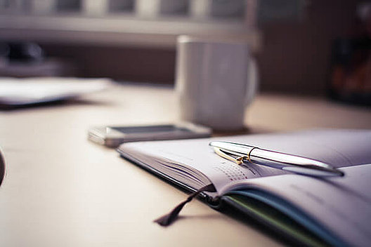 Aufgeschlagener Kalender mit Handy, Tasse und Stift. Foto von picjumbo.com auf Pexels