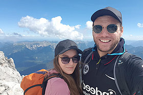 Mann und Frau auf der Zugspitze, im Hintergrund sieht man blauen Himmel und Berge. Marvin hat Mukoviszidose. 