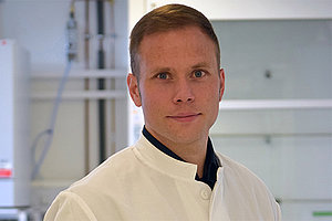 Porträt von Dr. Volker Winstel mit Laborkittel, im Hintergrund sieht man, dass er in einem Labor steht. 