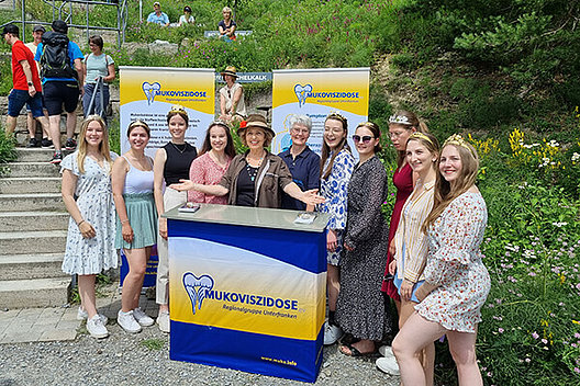 Michaela Mai mit den Weinprinzessinnen aus der Region Stetten bei der Weinlagenwanderung zugunsten des Mukoviszidose e.V. Michaela Mai mit den Weinprinzessinnen aus der Region Stetten bei der Weinlagenwanderung zugunsten des Mukoviszidose e.V. (mehrere Weinprinzessinnen stehen mit Schauspielerin Michaela May um einen Infostand der Mukoviszidose e.V. Regionalgruppe Unterfranken herum).