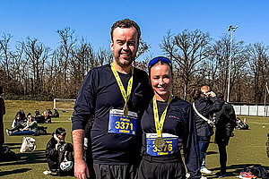 Florian mit Sophie Grace Holmes beim Frankfurter Halbmarathon Ein Mann und eine Frau in Sportkleidung mit Medaillen um den Hals lachen bei blauem Himmel in die Kamera.