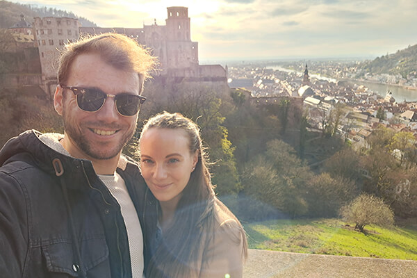 Marvin und seine Freundin im Urlaub, im Hintergrund ist grüne Landschaft und eine Burg zu sehen. 
