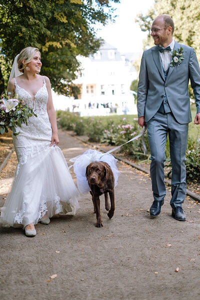 Julia im Hochzeitskleid mit ihrer Hündin Frieda und ihrem Mann 