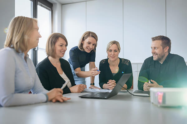 Besprechung im Mukoviszidose Institut Vier Frauen und ein Mann sitzen an einem Tisch mit laufendem Beamer. Besprechung im Mukoviszidose Institut