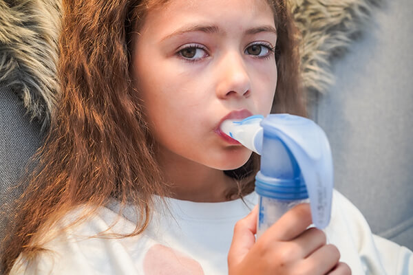 Carlotta (9 Jahre alt) sitzt im Sessel und inhaliert. Da sie Mukoviszidose hat muss sie täglich inhalieren. 